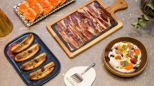 a table with different types of food and a pan of food at Hotel Indigo Barcelona Granvia Plaza Espana, an IHG Hotel in Barcelona