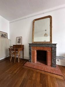 un salon avec une cheminée et un miroir dans l'établissement La petite Semuroise, à Semur-en-Auxois