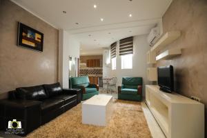 sala de estar con sofá de cuero negro y sillas verdes en Immeuble Gazbar, en Gabès