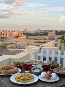 una mesa con platos de comida, huevos y patatas fritas en K Boutique Pyramids View West, en El Cairo