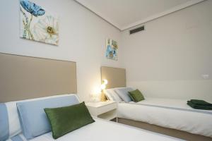 een witte slaapkamer met 2 bedden en een spiegel bij Paradise Rentals Denia VilaMar 2 in Denia