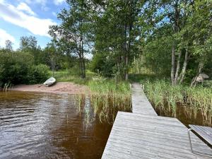 un puente de madera sobre un cuerpo de agua con un barco en Sauna cabin in the heart of Nuuksio National Park - Mökki Nuuksiossa, en Espoo