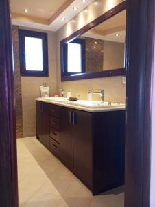 a bathroom with a sink and a large mirror at Kos Villa - Family Comfort with large Garden, Jacuzzi in Kos