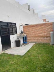 een achtertuin met een bakstenen muur en een gebouw met een poort bij Cómoda Casa cerca de Soledad-Aeropuerto in San Luis Potosí