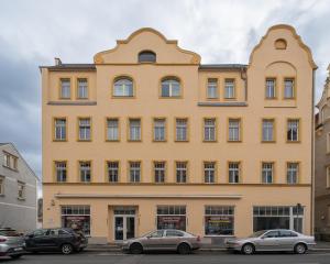 um edifício amarelo com carros estacionados em frente em BENVILLE Freital - WLAN - Nespresso Kaffee - Windbergblick em Freital