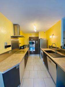 uma grande cozinha com paredes amarelas e electrodomésticos de aço inoxidável em Découvrez le charme au cœur de Gap em Gap