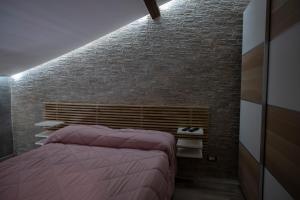 - une chambre avec un lit et un mur en briques dans l'établissement FACCI RI LUNA, à Nicolosi
