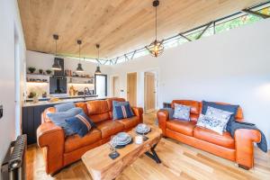 a living room with two leather couches and a table at Rowanbank Cabin - a gorgeous country escape in Kirkton of Auchterhouse