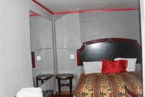 a bedroom with a bed with a red pillow and two stools at The Broadway Inn in Los Angeles