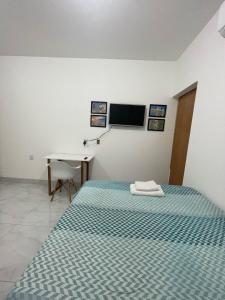 a bedroom with a bed and a desk and a television at Flat Completo Aparecida de Goiânia in Aparecida de Goiania