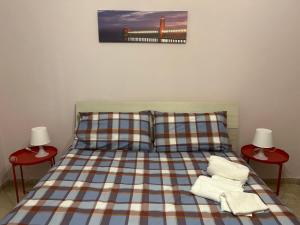 een bed met een geruite sprei en een pier bij Casa Cristina in Marino