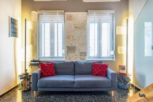 a blue couch in a living room with two red pillows at Arcade central retro apartment in Rethymno
