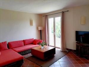 ein Wohnzimmer mit einem roten Sofa und einem TV in der Unterkunft Cozy 2-bedroom villa on river mouth in Terre Rouge