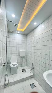 a white tiled bathroom with a toilet and a sink at Hotel Double1 in Islamabad