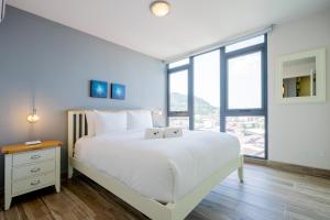 a bedroom with a white bed and a large window at Casco View By Wynwood House in Panama City