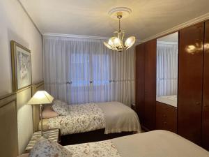 a bedroom with two beds and a mirror and a chandelier at Elegante apartamento con vistas al puerto de Santander in Santander