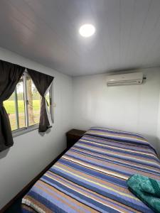 Bett in einem kleinen Zimmer mit Fenster in der Unterkunft Cabañas El Calabres in Tacuarembó