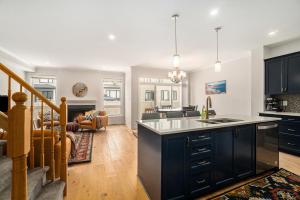 a kitchen with black cabinets and a living room at Fully Furnished 4 Bedroom House in Ottawa in Ottawa