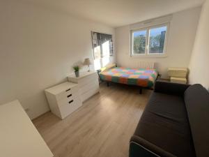 ein kleines Zimmer mit einem Bett und einem Sofa in der Unterkunft Villa plein pied in Lingolsheim