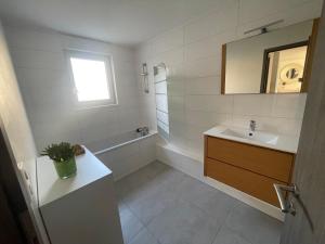 uma casa de banho com um lavatório, uma banheira e um espelho. em Villa plein pied em Lingolsheim