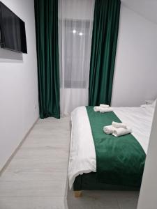una camera da letto con tende verdi e un letto con asciugamani di Gold Tag Apartament a Timişoara