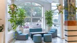 - un hall avec des chaises bleues, une table et des fenêtres dans l'établissement HOTEL KAISER, à Sousse