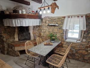 a dining room with a table and chairs and a stone fireplace at Holiday House VUKI in Nedeščina