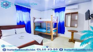 Hotel la Bendición في Moñitos: غرفة نوم مع سرير وسرير بطابقين مع ستائر زرقاء