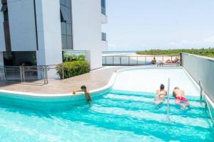 un groupe de personnes dans une piscine située dans un bâtiment dans l'établissement Apartamento com Vista Deslumbrante à Beira Mar., à Récife