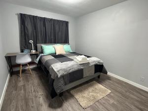 1 dormitorio con 1 cama con escritorio y silla en Cute Highland Park Entire Unit A en Calgary