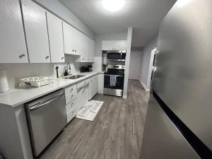 cocina con armarios blancos y nevera de acero inoxidable en Cute Highland Park Entire Unit A en Calgary