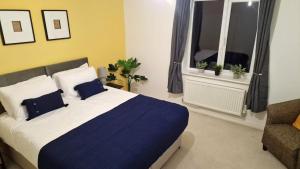 a bedroom with a bed and a chair and two windows at Margam's Alvington House for Business Travellers, Relocator or Families with FREE Parking, High Speed Internet and fully equipped kitchen 