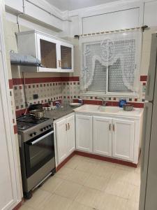 uma cozinha com armários brancos e um fogão em Studio cité elwahat em La Marsa