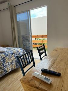 a room with a wooden table and chairs and a bed at Hospedaria Cumbuco - Kitnets Completas in Caucaia