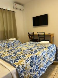 a bedroom with two beds and a table with chairs at Hospedaria Cumbuco - Kitnets Completas in Caucaia