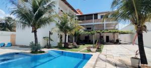 a swimming pool in front of a building with palm trees at Hospedaria Cumbuco - Kitnets Completas in Caucaia