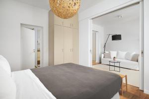a white bedroom with a bed and a living room at Crete - Heraklion Sea View Apartment 1 in Heraklio Town