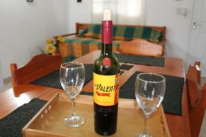 a bottle of wine sitting on a table with two wine glasses at Hospedaje BAHUINIAS II in Federación +17 photos