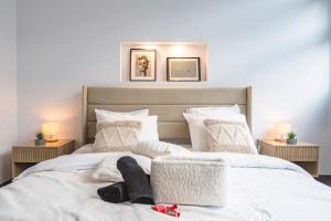 Schlafzimmer mit einem Bett mit weißer Bettwäsche und Kissen in der Unterkunft Le majestueux • Jacuzzi • Cinema • Netflix • Wifi in Reims