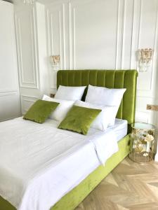 un letto verde con lenzuola bianche e cuscini verdi di Brand new 1-bedroom apartment in city centre a Gori