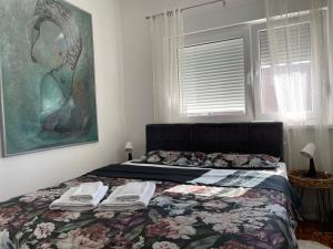 a bedroom with a bed with a blanket and a painting at Sunny apartment in Vršac