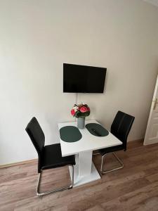 una scrivania bianca con due sedie e una televisione su un muro di One-Room Danube Apartment a Vienna