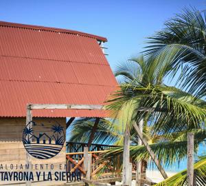 a building with palm trees in front of the beach at Cabaña Rincón de los Cocos in Santa Marta