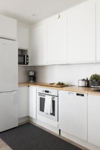a white kitchen with white cabinets and appliances at Stunning design apartment with sauna & free parking in Helsinki