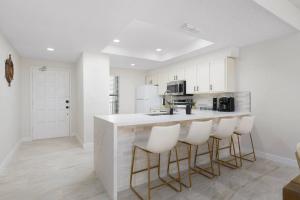 a kitchen with white cabinets and a bar with stools at Enjoy the Best Ocean Views in a Beach Front Condo in South Padre Island