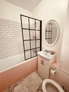 a bathroom with a toilet and a sink and a mirror at Stylish Pink Oasis in Wimbledon in London