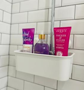 a shelf in a bathroom with toiletries and cosmetics at Stylish Pink Oasis in Wimbledon in London
