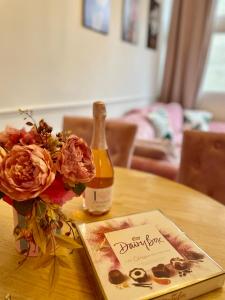 a bottle of wine on a table with a book and flowers at Stylish Pink Oasis in Wimbledon in London