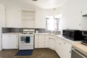 a kitchen with white cabinets and a white stove top oven at Copenhagen Cottage in Solvang