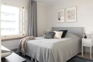 een witte slaapkamer met een bed en een raam bij Stunning design apartment with sauna & free parking in Helsinki